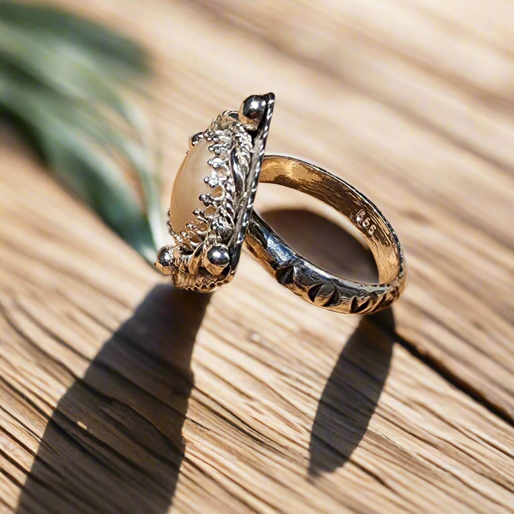 Silver ring with a decorative design on a wooden surface