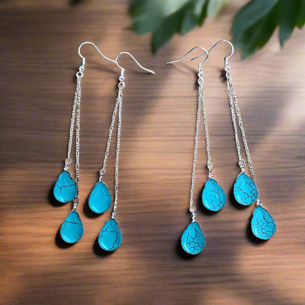 Turquoise teardrop earrings on a wooden surface