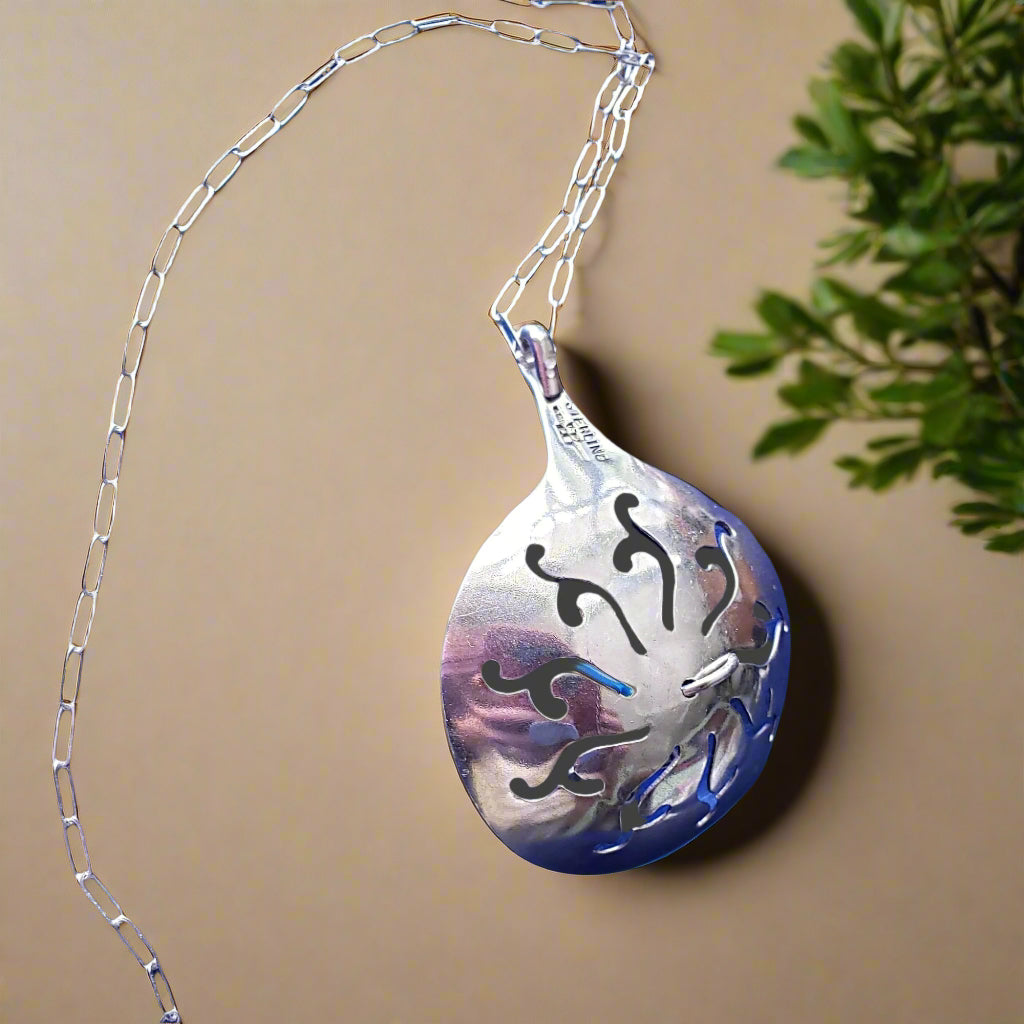 Decorative dpoon pendant with chain on a beige background