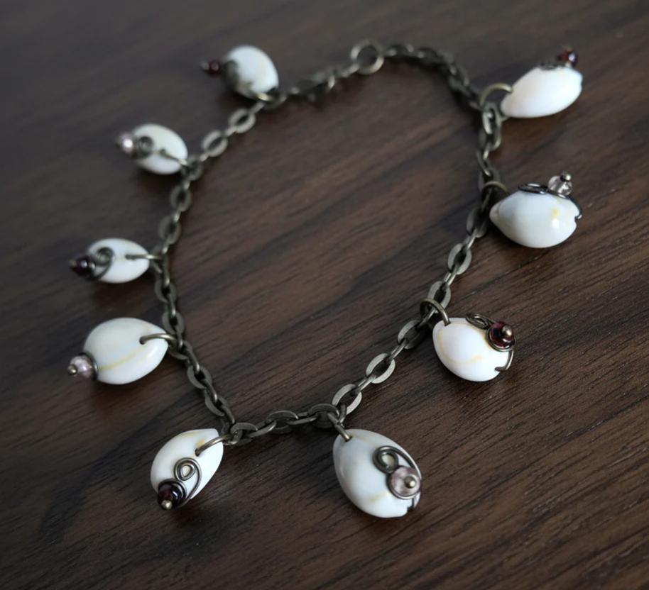 Coastal cowrie shell anklet bracelet on dark wood background with wire wrapped glass beads