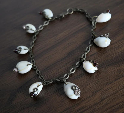 Coastal cowrie shell anklet bracelet on dark wood background with wire wrapped glass beads
