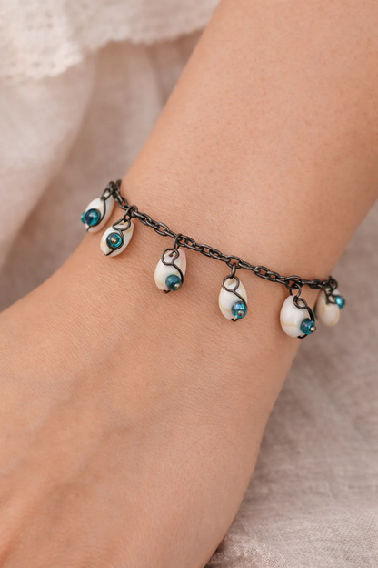 Handmade shell charm bracelet worn on wrist with green and blue beads on oxidized oval link chain