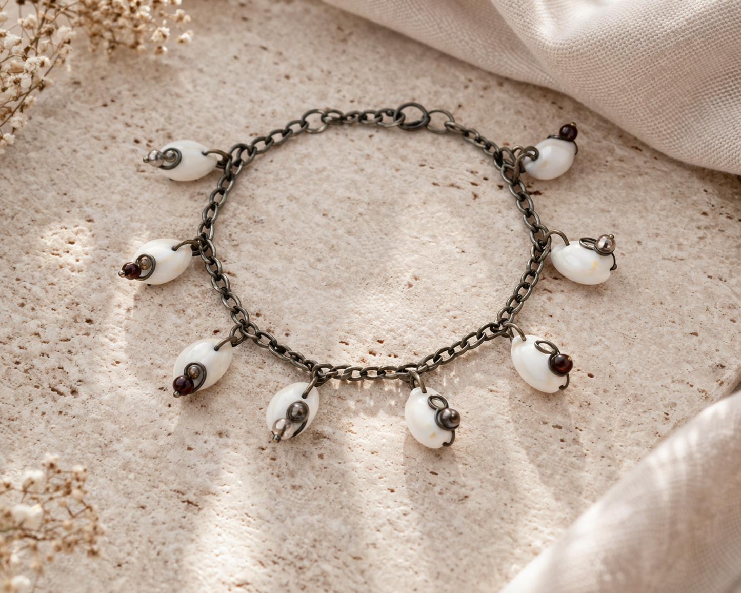 Cowrie shell anklet bracelet styled on stone surface with clear and brown beads coastal jewelry