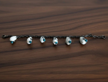 Close up of shell bracelet stretched out showing alternating green and blue beads on oxidized chain