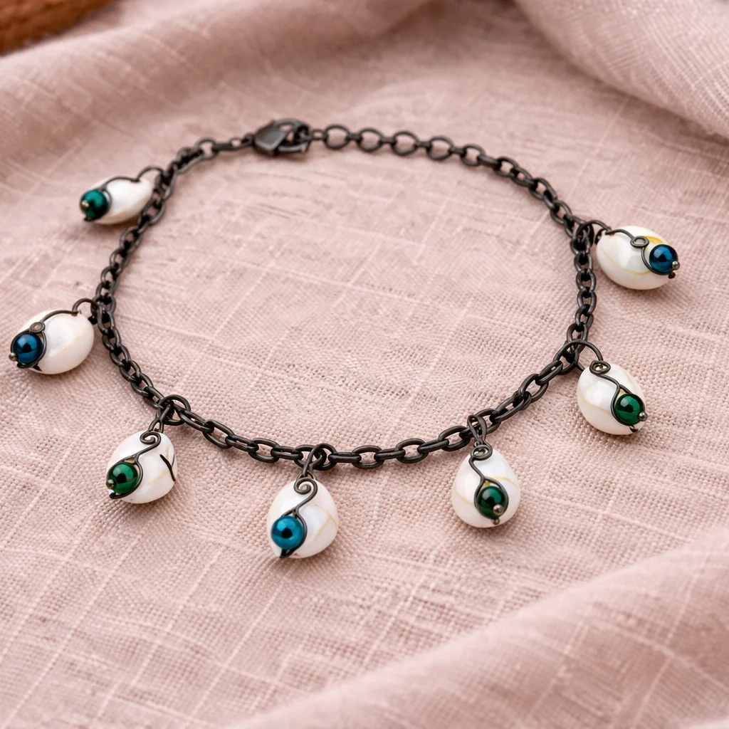 Coastal shell bracelet styled on neutral fabric with green and blue beads and vintage style chain