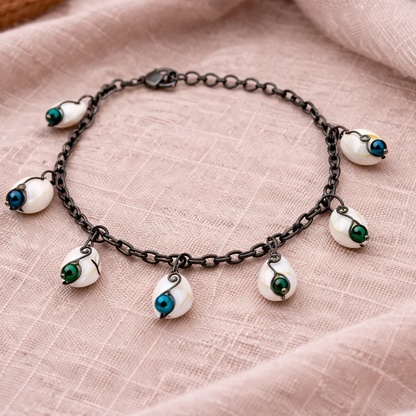 Coastal shell bracelet styled on neutral fabric with green and blue beads and vintage style chain