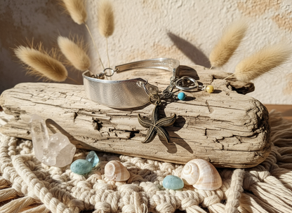Jewelry set with starfish charm on a piece of driftwood with shells and crystals.