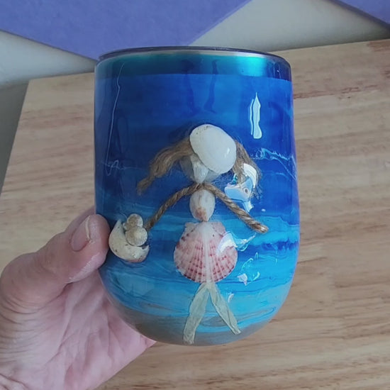hand holding a blue 12oz shell people wine tumbler with a real seashell figure