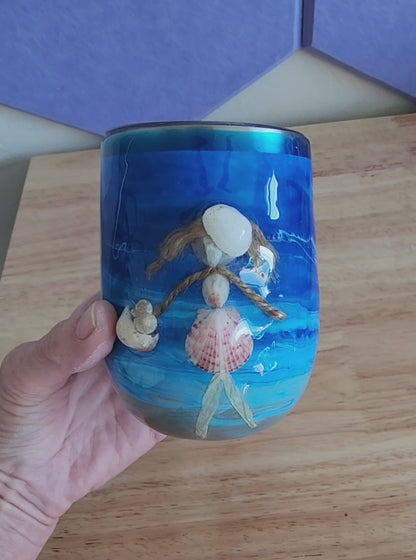 hand holding a blue 12oz shell people wine tumbler with a real seashell figure