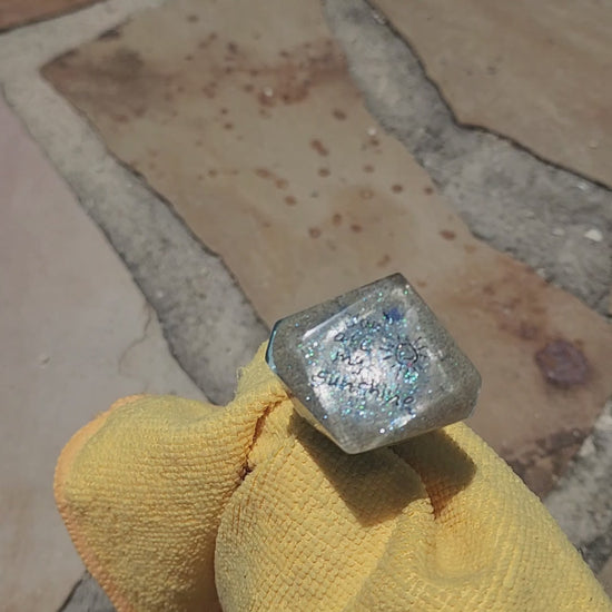 Video showing a rotating close-up of a layered ocean resin bottle stopper, highlighting the shimmering blue waves and the sweet You are my sunshine inscription embedded in the sand top.