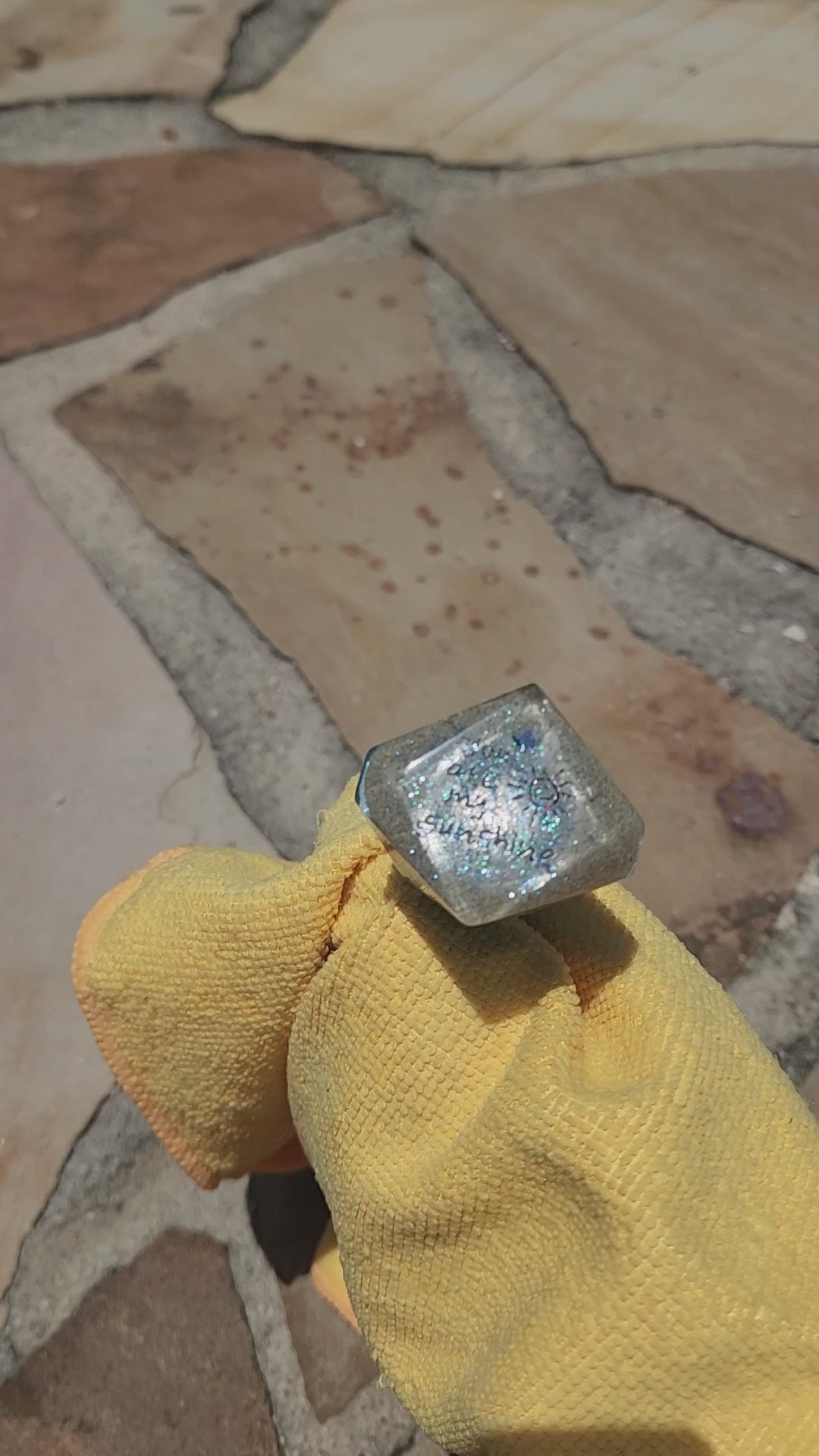 Video showing a rotating close-up of a layered ocean resin bottle stopper, highlighting the shimmering blue waves and the sweet You are my sunshine inscription embedded in the sand top.