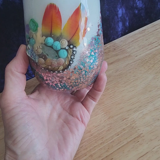 Hand holding coastal boho glitter wine tumbler with feathers and turquoise stones