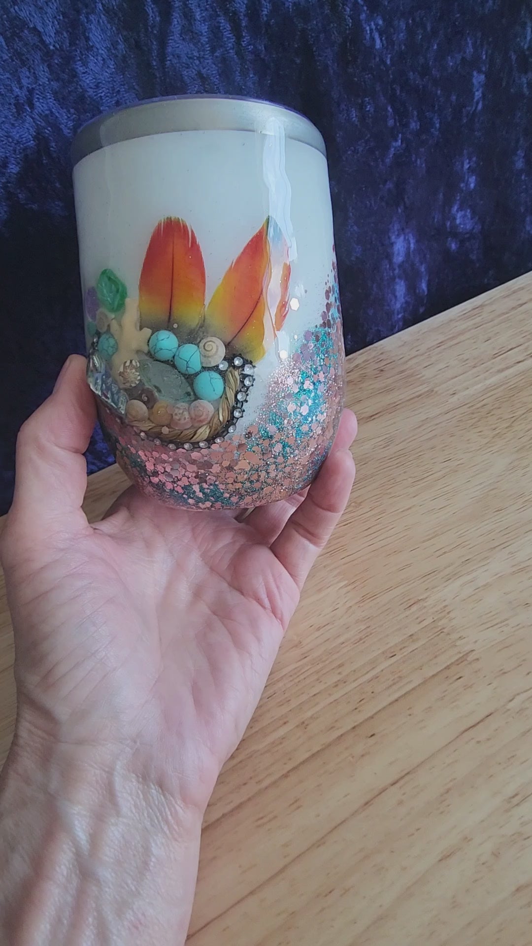 Hand holding coastal boho glitter wine tumbler with feathers and turquoise stones