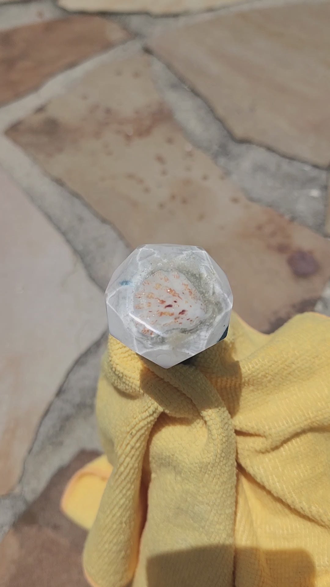 Birds-eye view of the multi-faceted crystal top of a handmade resin bottle stopper, highlighting the embedded shimmering details and crisp white crest