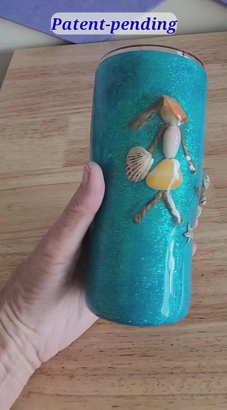 Video: hand holding a teal 20oz shell people tumbler with real seashell details