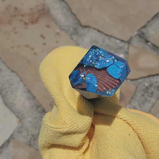 Handmade sapphire blue geometric resin wine stopper with embedded seashell, close-up
