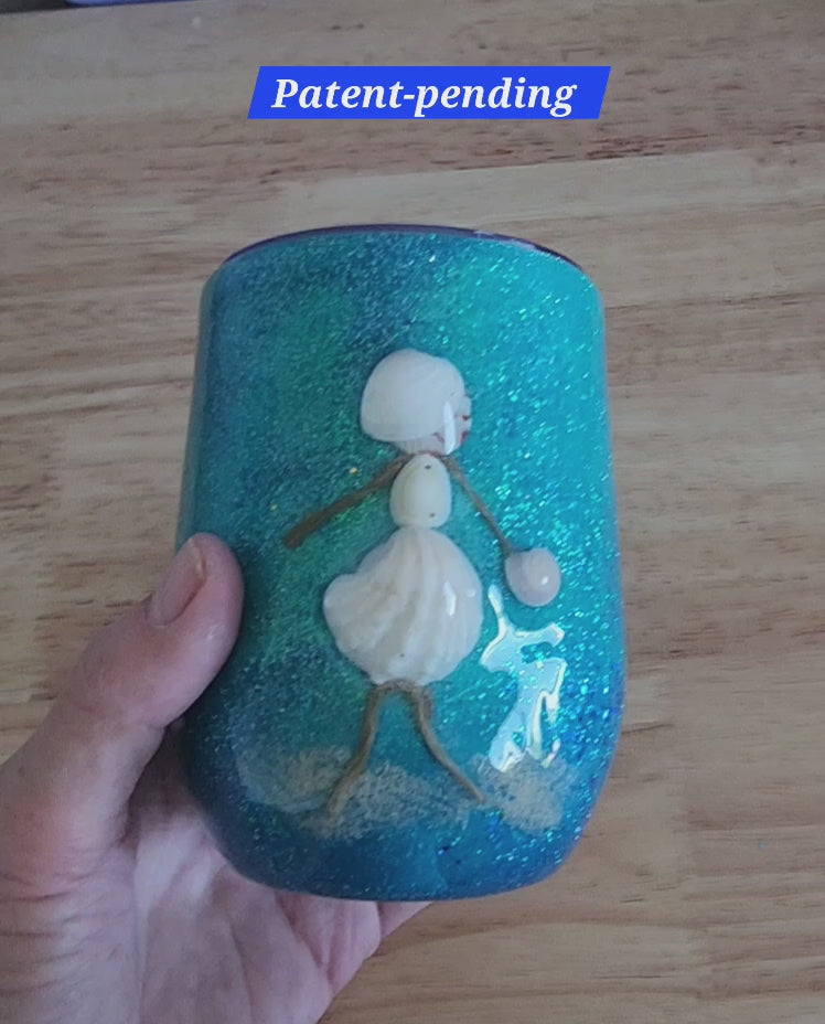 Video: hand holding a teal shell people wine tumbler with a white seashell figure