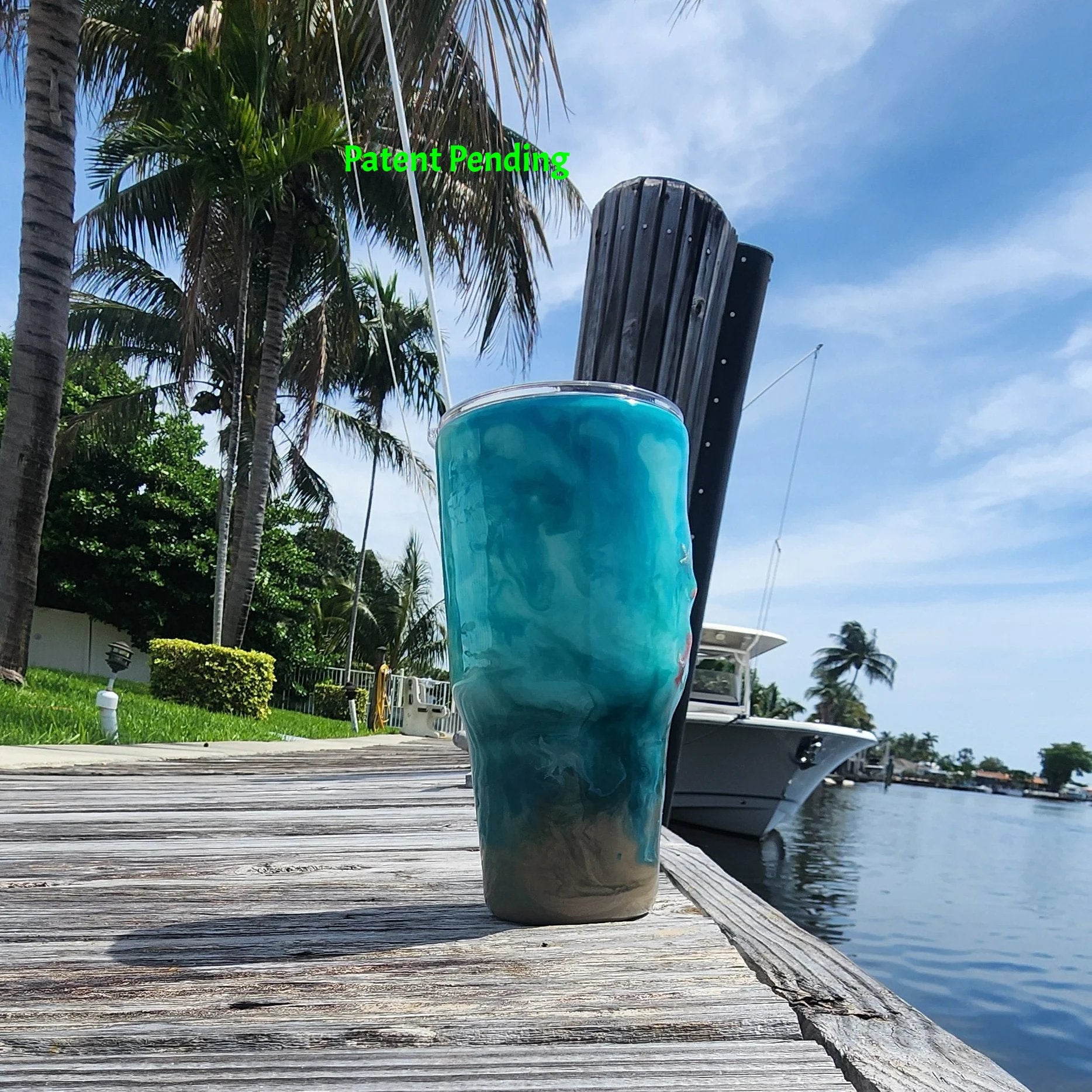 Right side view of handmade 30oz teal Caribbean coastal fishing tumbler with real fish hooks, glow-in-the-dark shrimp lures, silver crab and starfish charms, and sea snail shells - Hook & Tumble™ by SoFlo Boho Boutique, displayed on a South Florida marina dock with palm trees and water in the background.