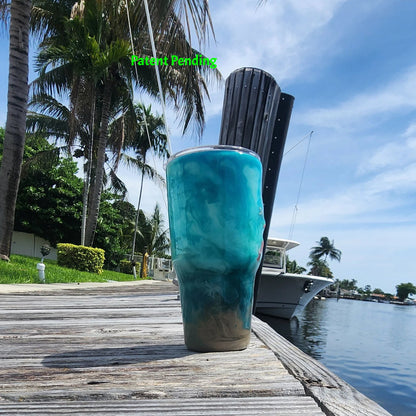 Right side view of handmade 30oz teal Caribbean coastal fishing tumbler with real fish hooks, glow-in-the-dark shrimp lures, silver crab and starfish charms, and sea snail shells - Hook & Tumble™ by SoFlo Boho Boutique, displayed on a South Florida marina dock with palm trees and water in the background.