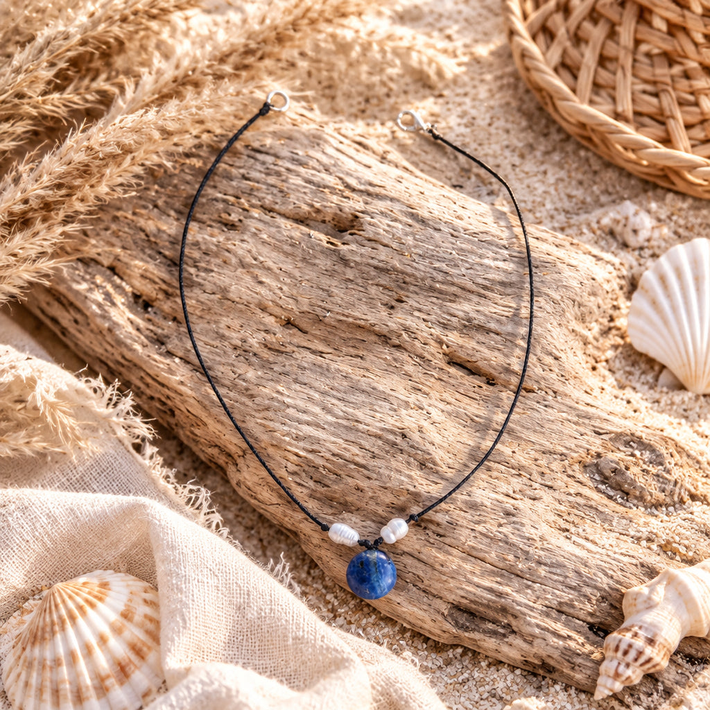 Handmade blue gemstone necklace displayed with seashells and driftwood