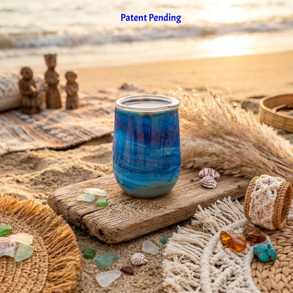 Handmade blue ocean wine tumbler with real seashells on driftwood at the shoreline
