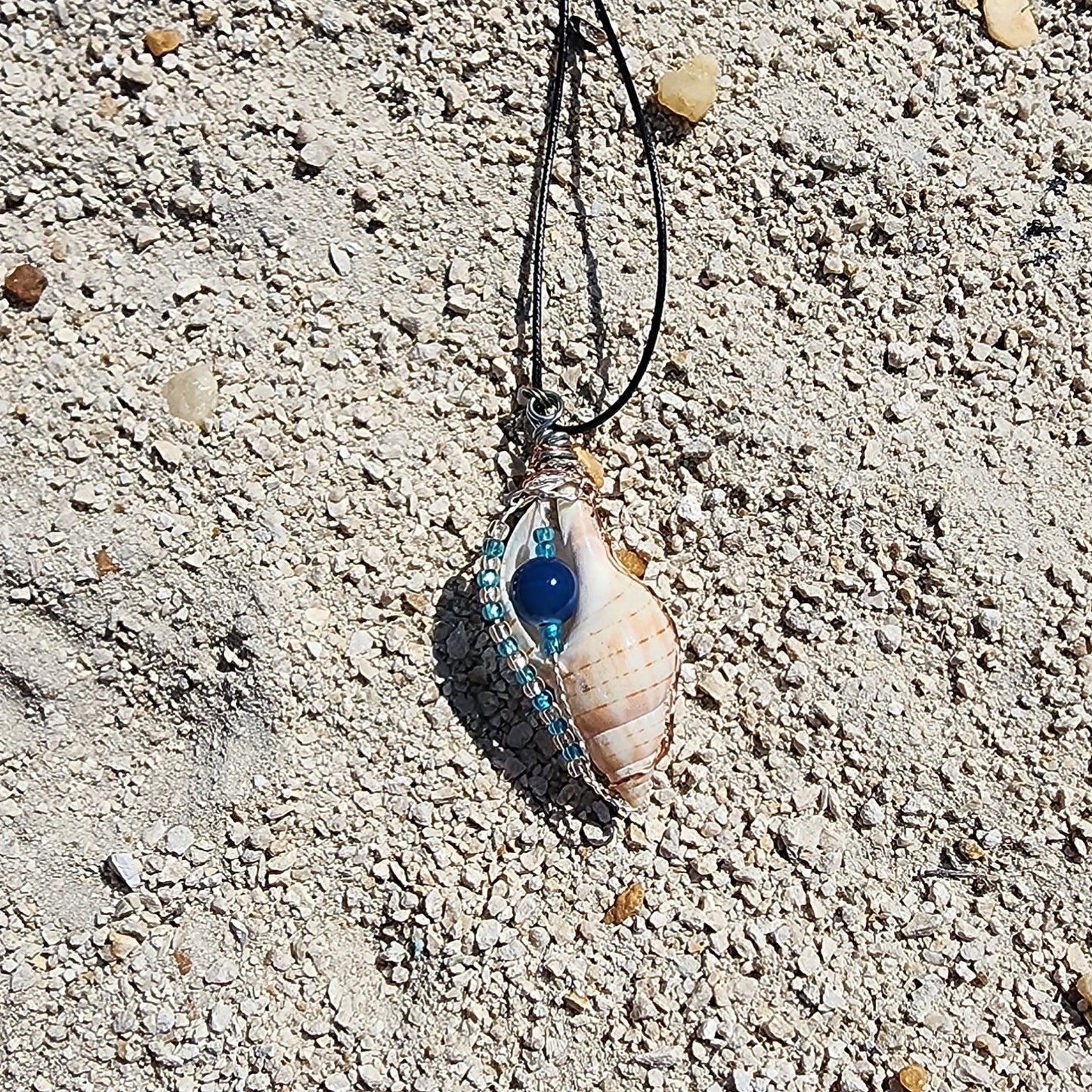 Handmade tulip shell pendant necklace with copper wire wrap, blue ceramic bead, and glass beads on cord