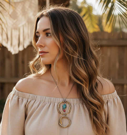 Woman wearing handmade brass turtle pendant necklace with howlite turtle and hammered circles