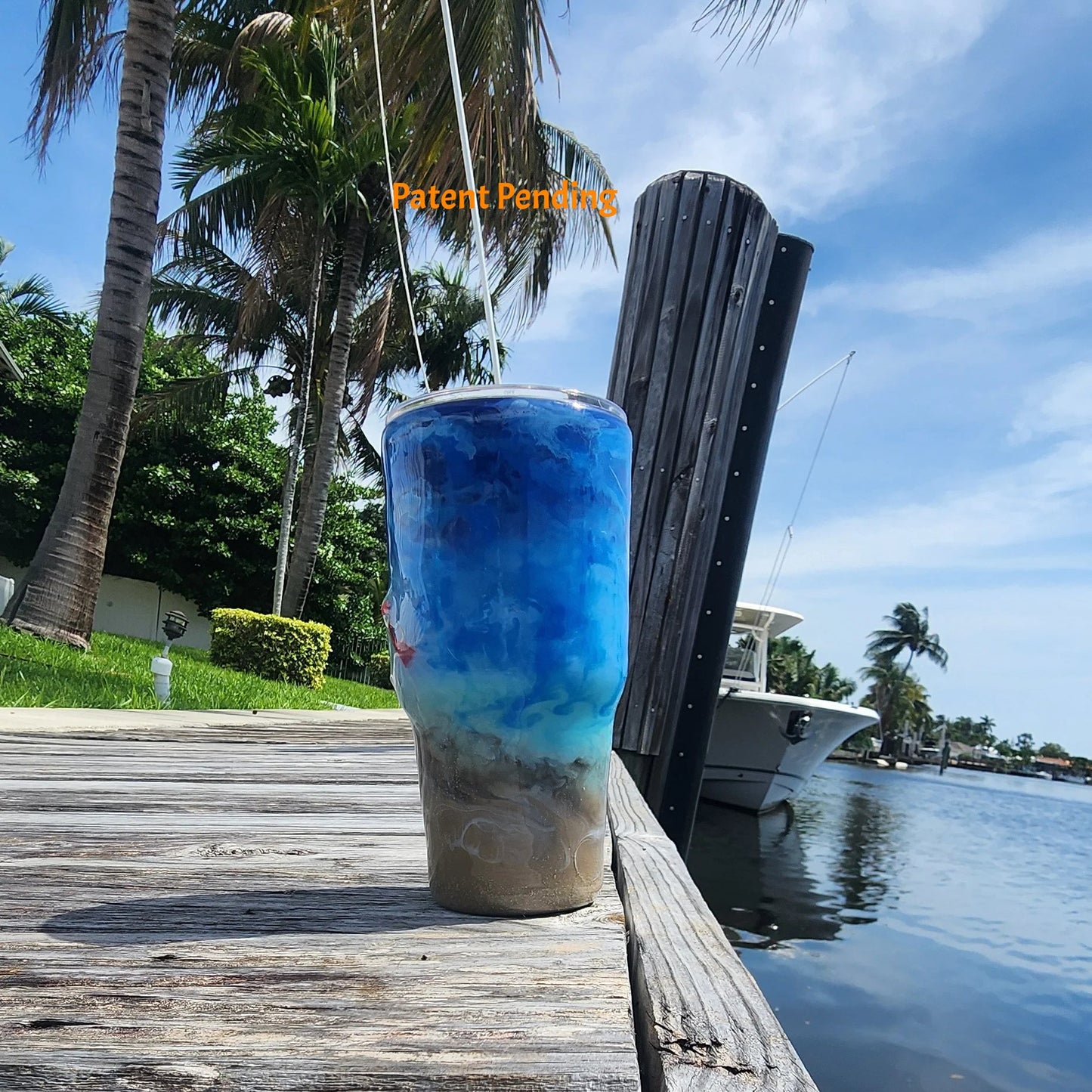 Right side view of Crystal Shore Deep 30oz fishing tumbler on South Florida marina dock showing saltwater fish hooks and glow-in-the-dark baitfish rig detail with waterway in background. Hook & Tumble™ by SoFlo Boho Boutique, Patent Pending.