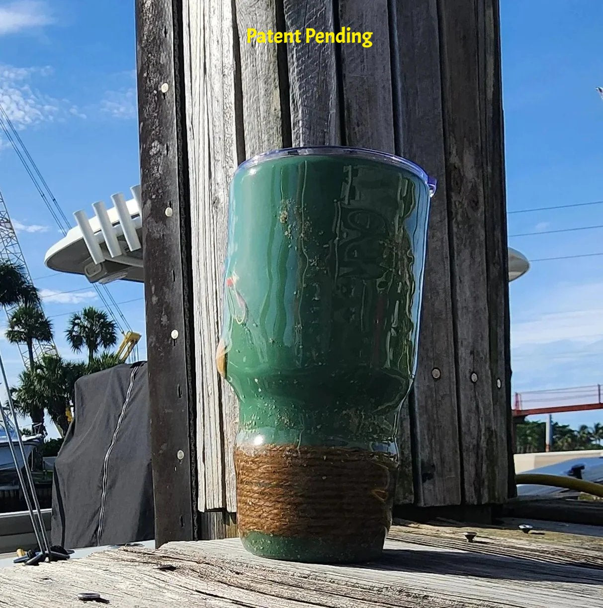 Marsh Tide 30oz Hook & Tumble Patent Pending fishing tumbler side view on marina dock showing seashell detail and natural rope wrapped base with clear lid