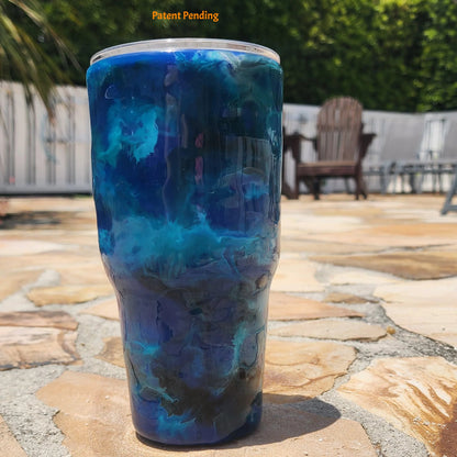 Blue Open Water backside of fishing hook tumbler photographed at waterfront dock, showing deep cobalt and teal handmade 30oz coastal drinkware