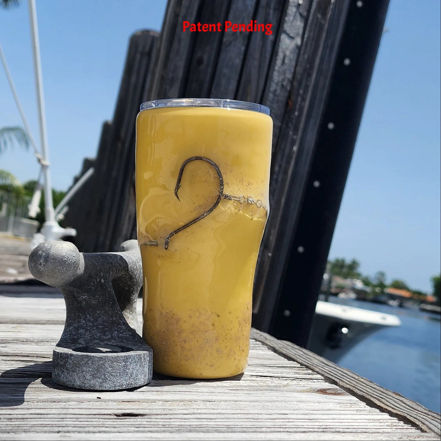 Golden Hour 20oz Hook & Tumble fishing tumbler front view showing authentic fishing hook and sand accent on golden yellow with dock and boat in background