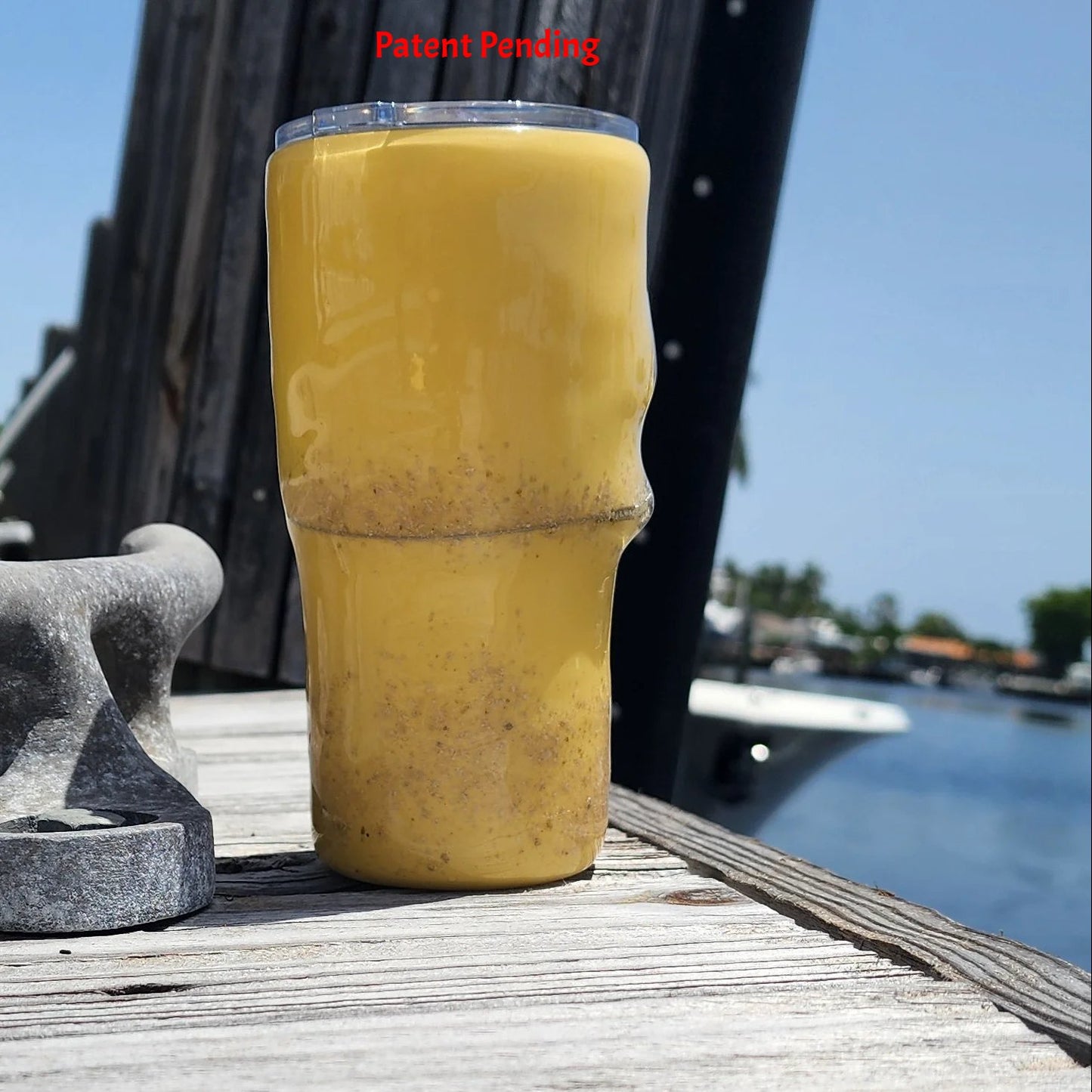 Golden Hour 20oz Hook & Tumble fishing tumbler left side view showing golden yellow with sand accent, dock and boat in background