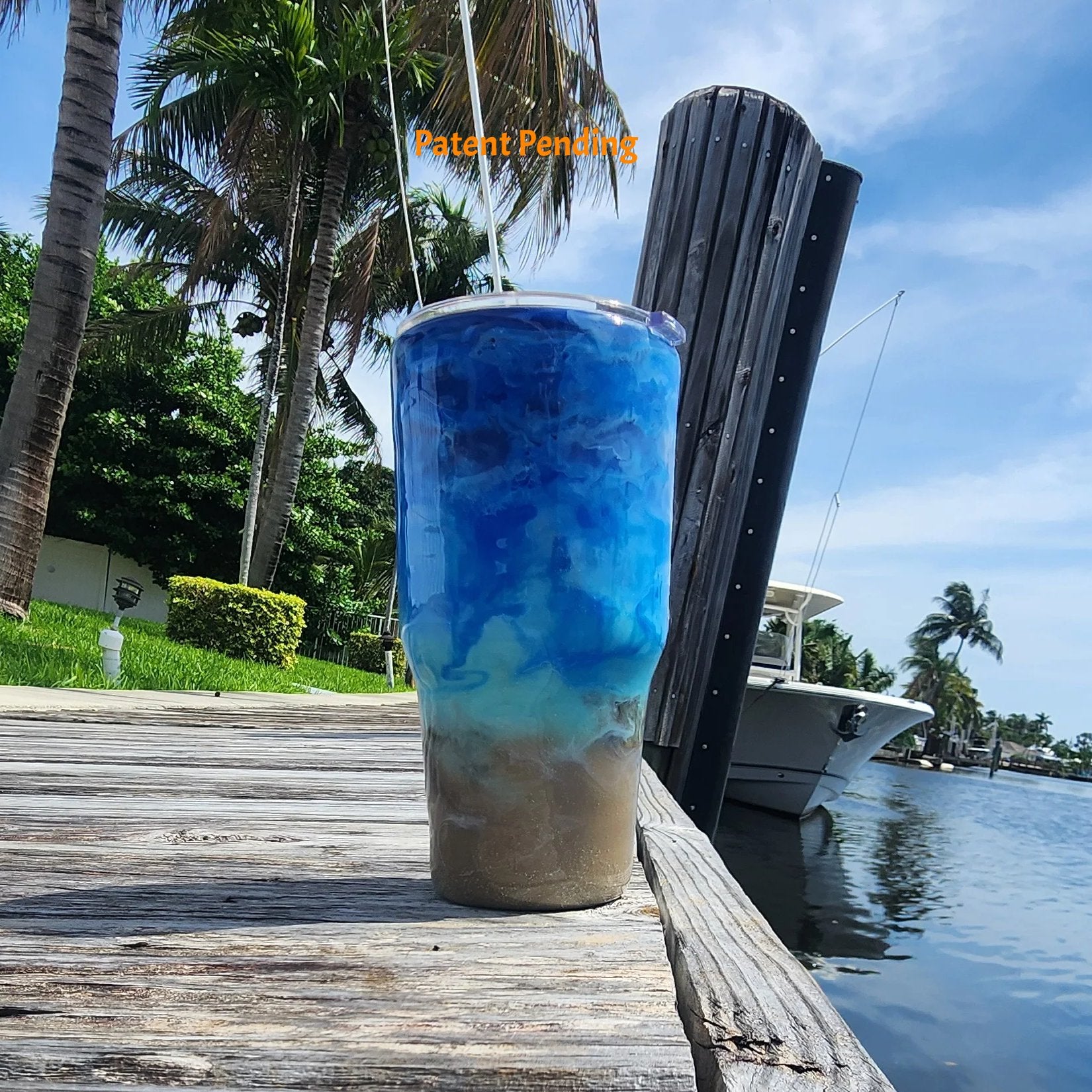 Back view of Crystal Shore Deep 30oz fishing tumbler on South Florida marina dock showing full sandy shore to crystal turquoise to deep cobalt blue ocean design with palm trees and boat in background. Hook & Tumble™ by SoFlo Boho Boutique, handcrafted in South Florida, Patent Pending.