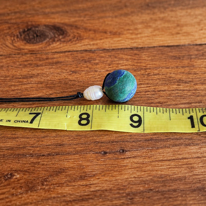 Teal gemstone pendant and pearl bead necklace size reference on tape measure