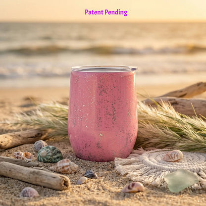 Back side of handmade pink 12oz Saltwater Sips tumbler in beach grass with scattered shells