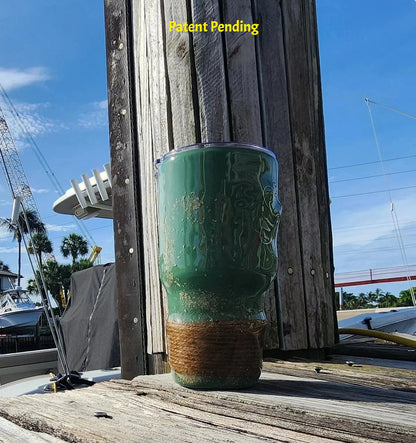 Marsh Tide 30oz Hook & Tumble Patent Pending fishing tumbler on marina dock right side view, glow in the dark shrimp hooks and seashell with natural rope wrapped base against blue sky