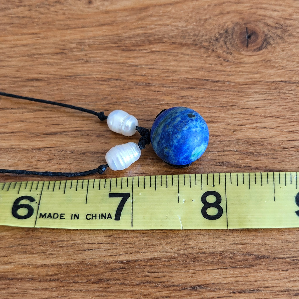 Blue gemstone pendant and pearl bead necklace size reference on tape measure