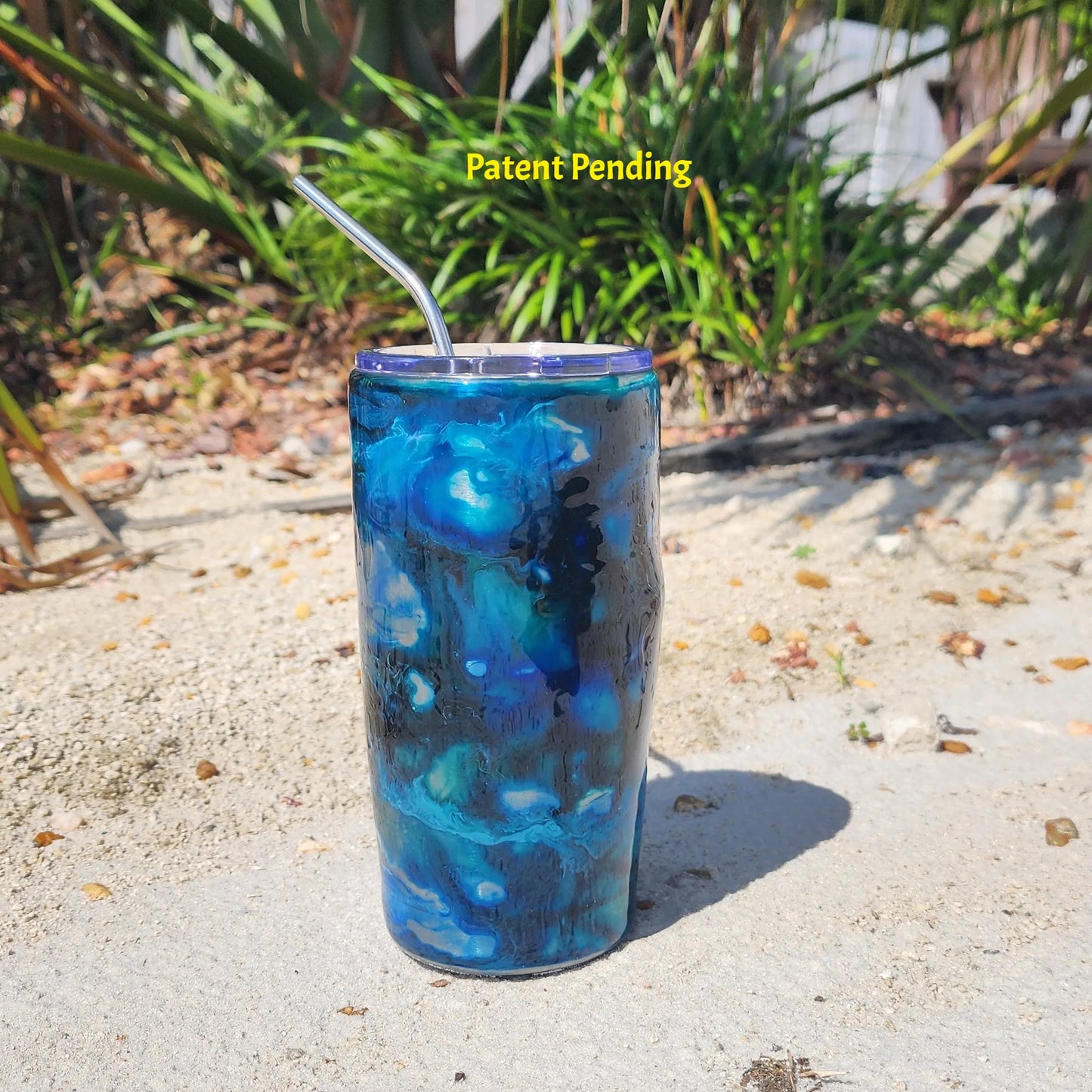 Blue Lagoon 20oz Hook & Tumble fishing hook tumbler on sand, deep navy and cobalt blue coastal drinkware