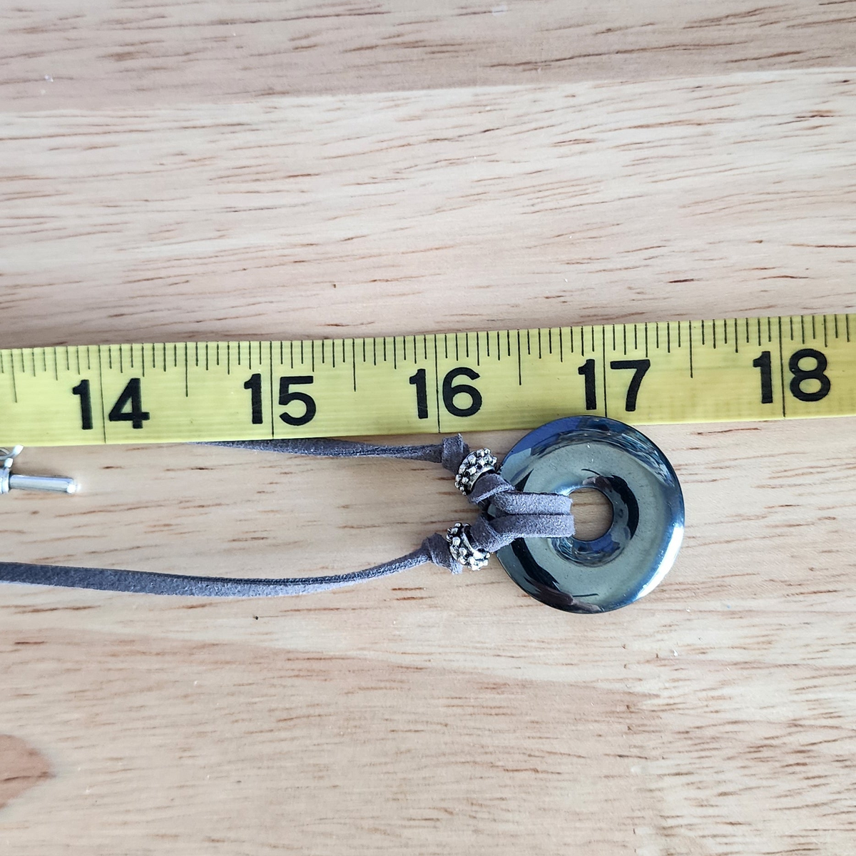 Hematite Stone adjustable choker necklace on gray faux suede cord on a measure tape