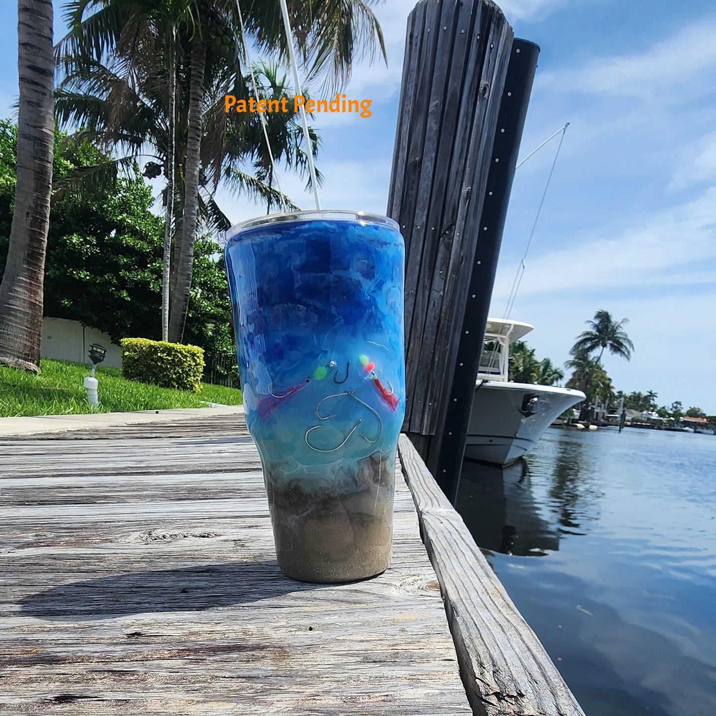 Crystal Shore Deep 30oz fishing tumbler front view on South Florida marina dock with palm trees, boat and waterway. Real saltwater fish hooks, glow-in-the-dark speckled shrimp hook and baitfish rig, sandy shore to crystal turquoise to deep cobalt blue ocean design. Hook & Tumble™ by SoFlo Boho Boutique, Patent Pending, handcrafted in South Florida.
