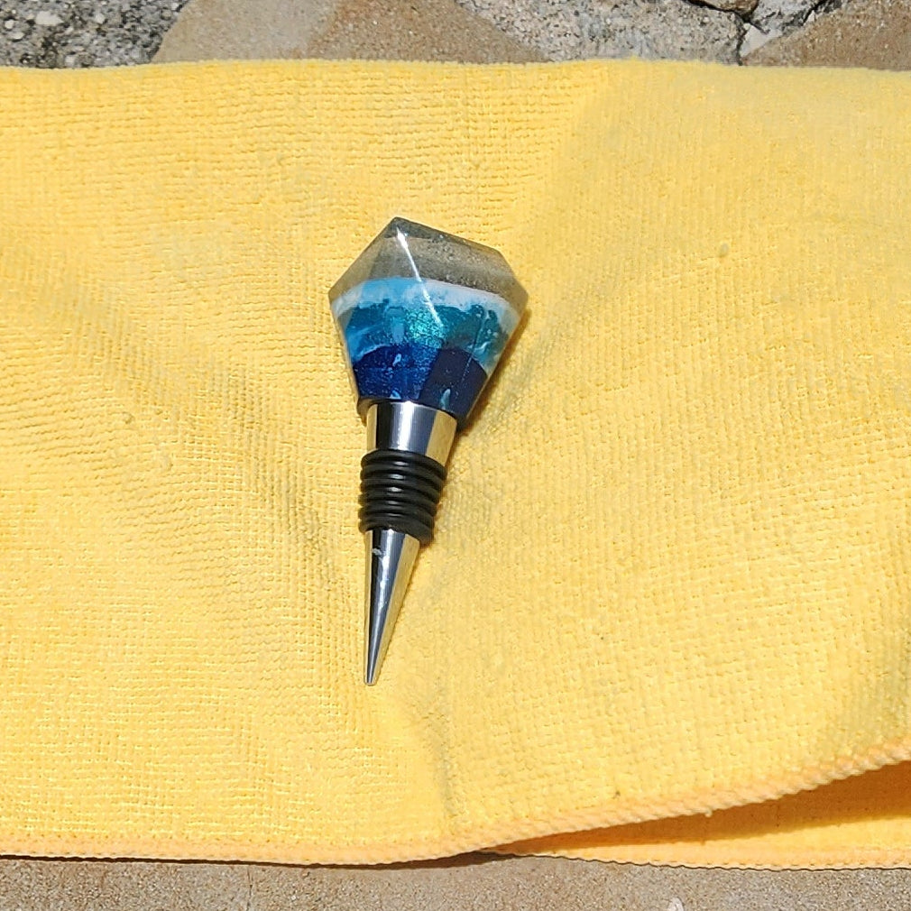 Side profile of a handcrafted multi-layered resin wine stopper highlighting the polished geometric facets and secure rubber gaskets on the alloy stem.