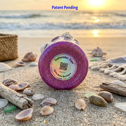 botton view of pink and purple shell figure tumbler in beach grass and driftwood on the sand