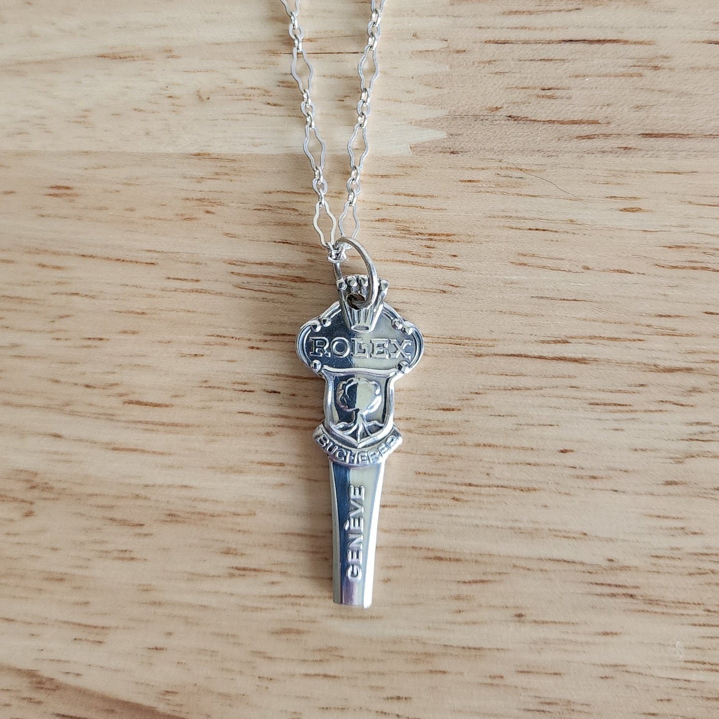 Rolex Bucherer vintage silver spoon handle pendant on wood surface, handmade necklace