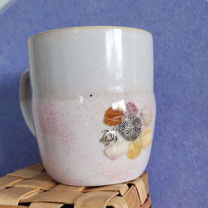 Close up of real seashells and silver sand dollar & turtle charm on ceramic mug