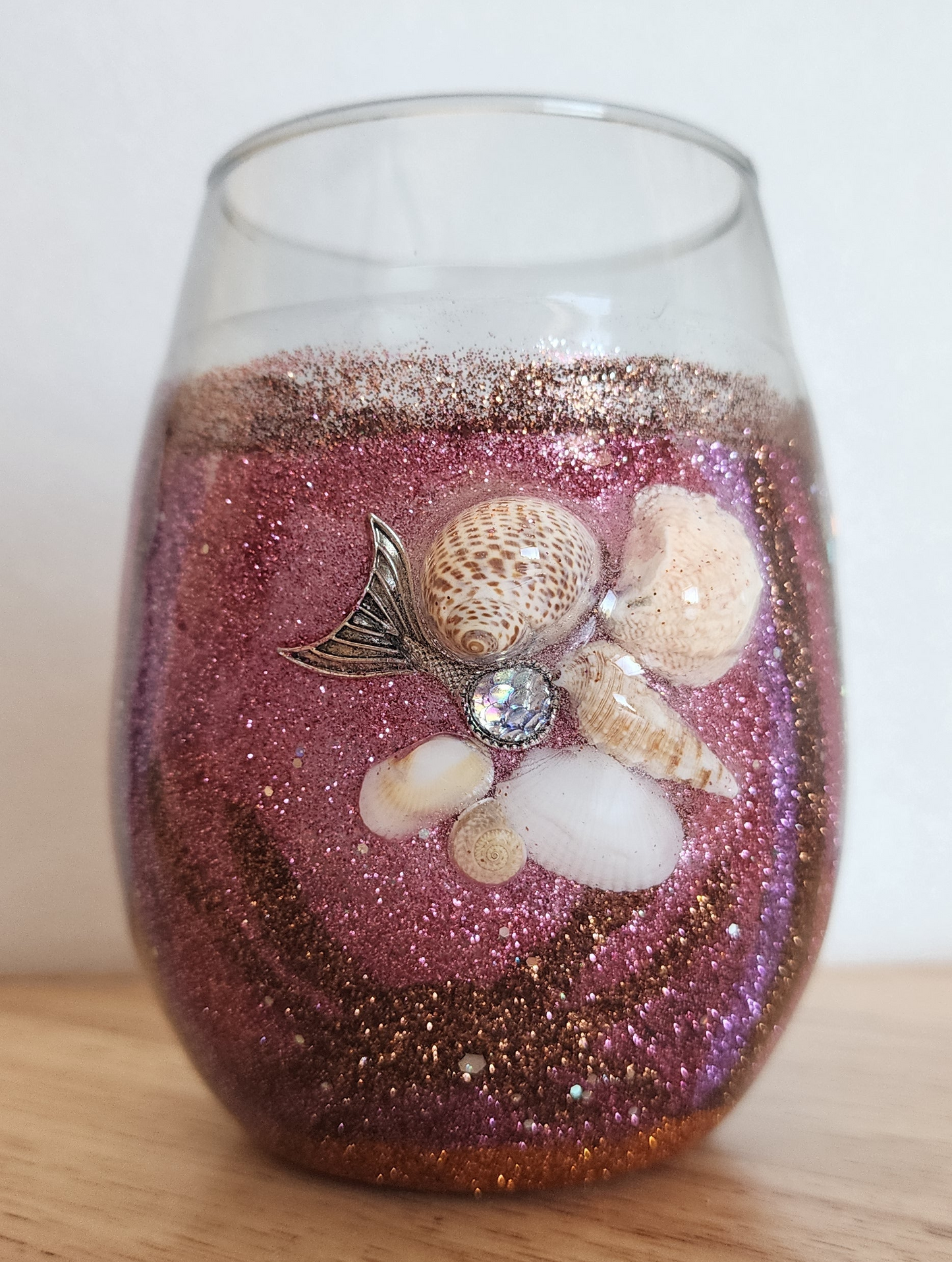 Burungdy, brown and pink glitter wine glass with Seashell on table with white background
