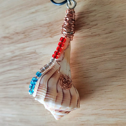 Close up of wire wrapped seashell pendant showing copper coil bail and glass bead detail on black cord