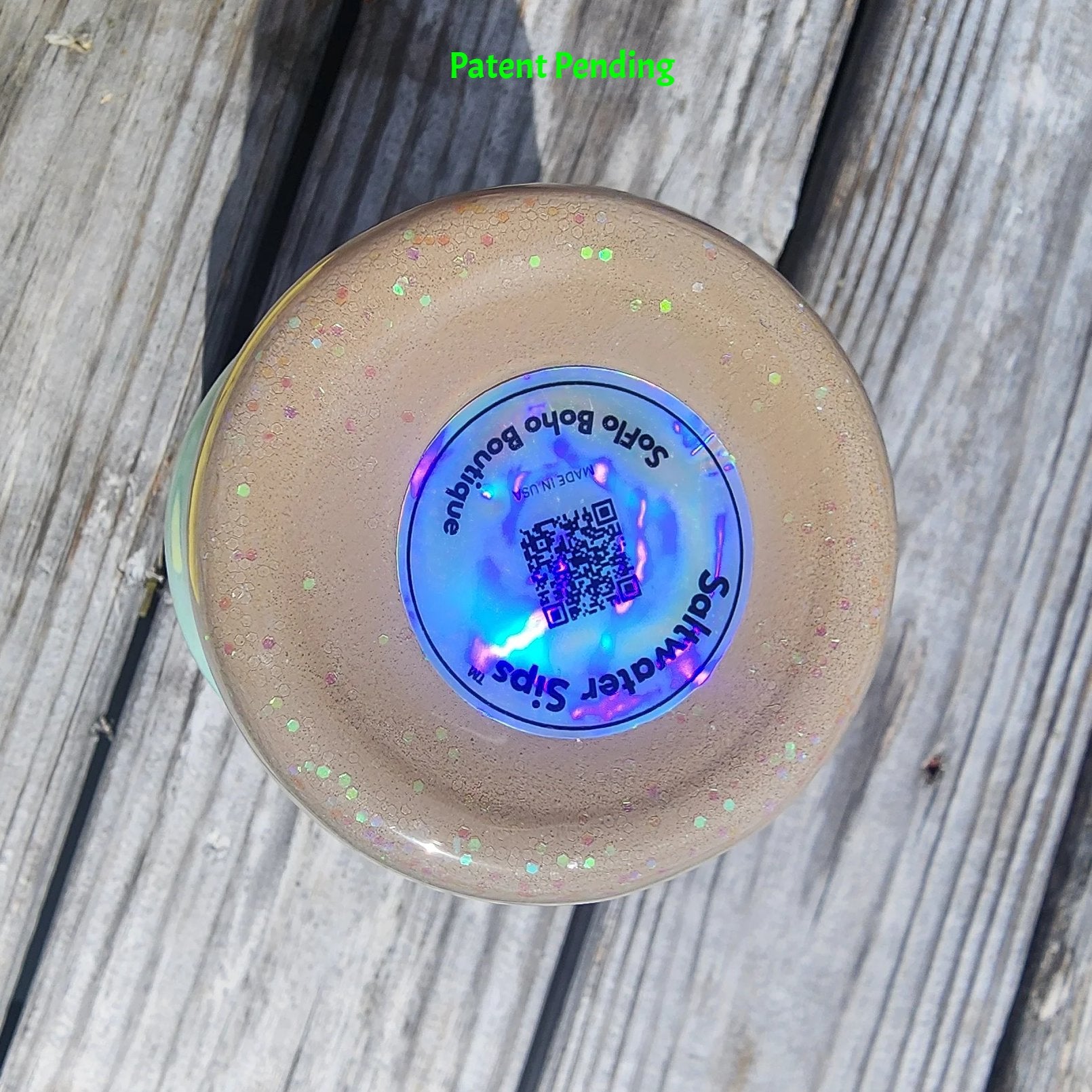 Bottom view of Caribbean Glow Shell Glitter 30oz tumbler on South Florida marina dock showing holographic Saltwater Sips™ brand label with QR code and SoFlo Boho Boutique branding. Made in USA, Patent Pending.