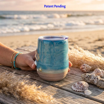 Hand holding a handmade teal shell people wine tumbler at sunset on a South Florida beach