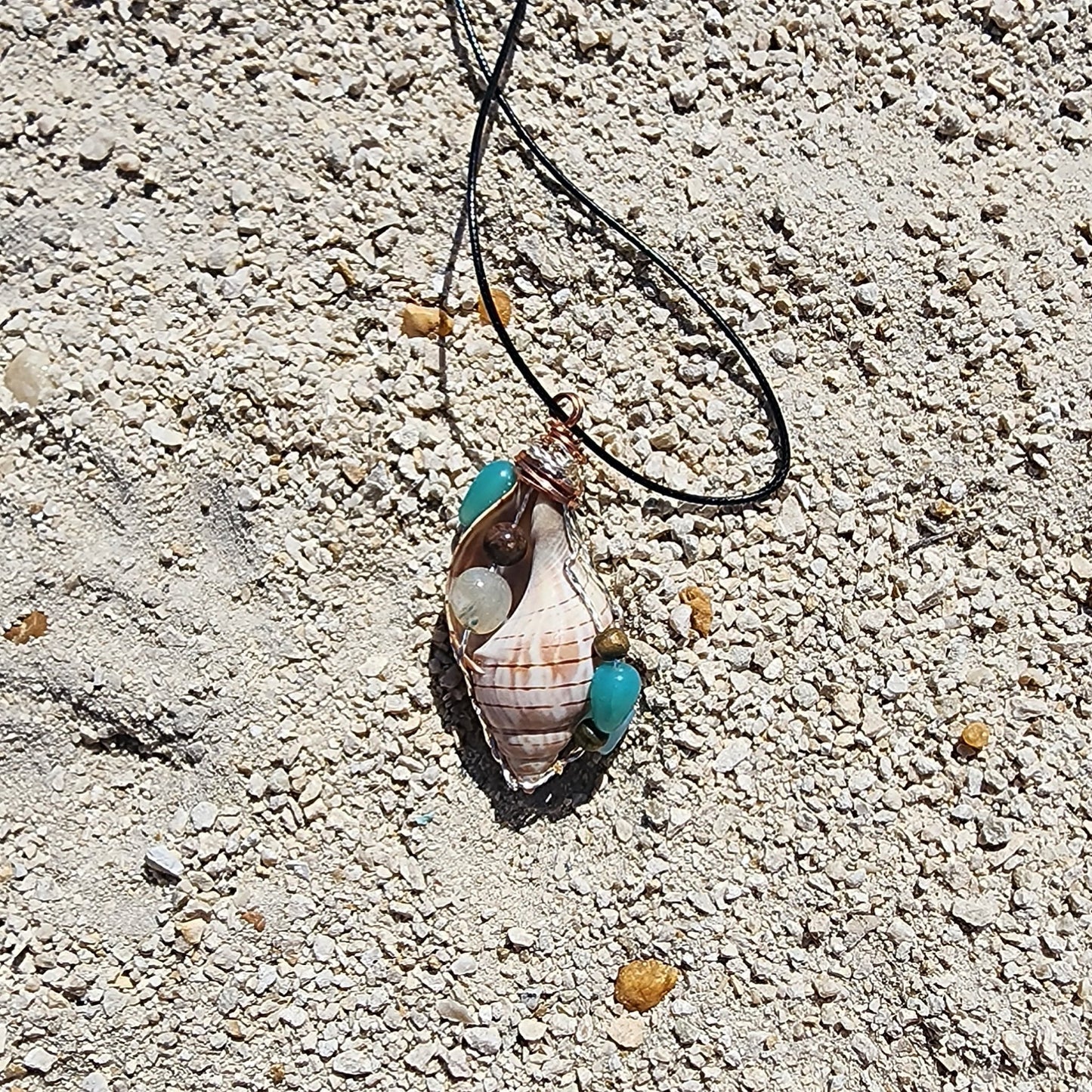 Handmade tulip shell pendant necklace with mixed metal wire wrap, turquoise beads, and wood accents on cord